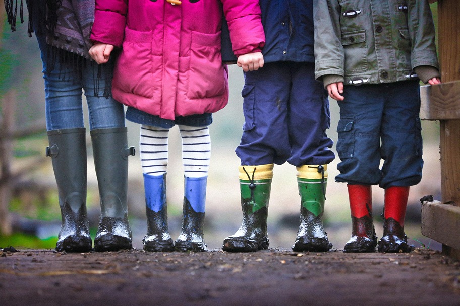 four kids standing side by side in rain boots