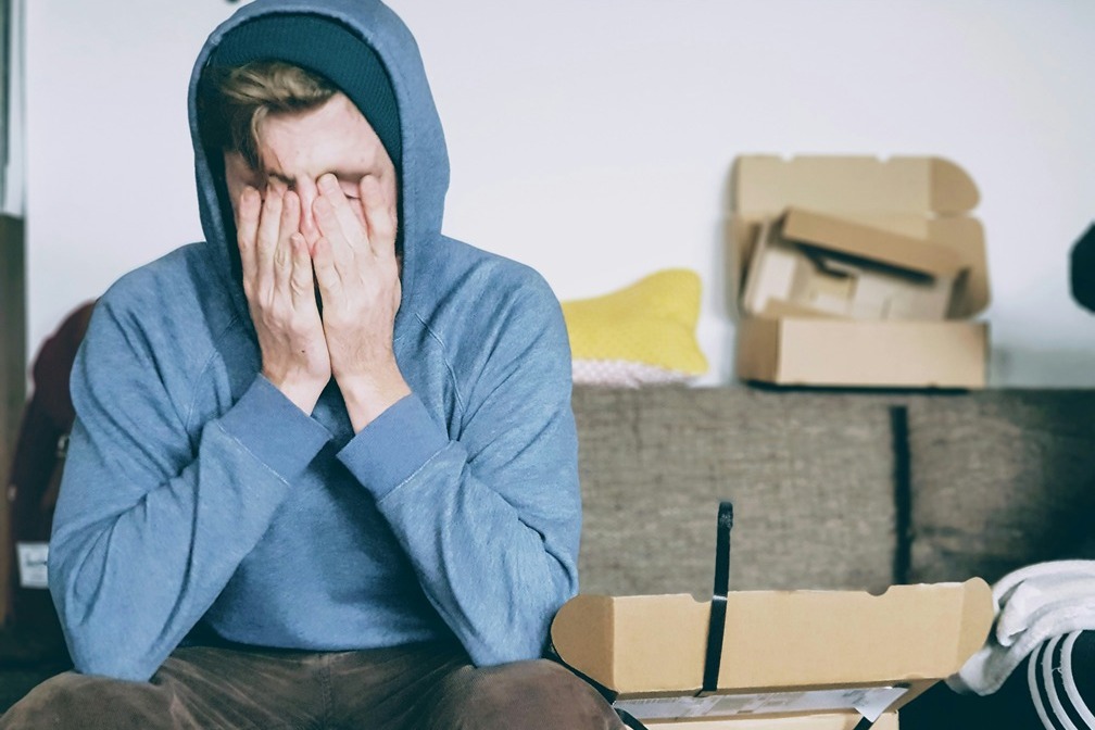 teen in hoodie with face resting in hands